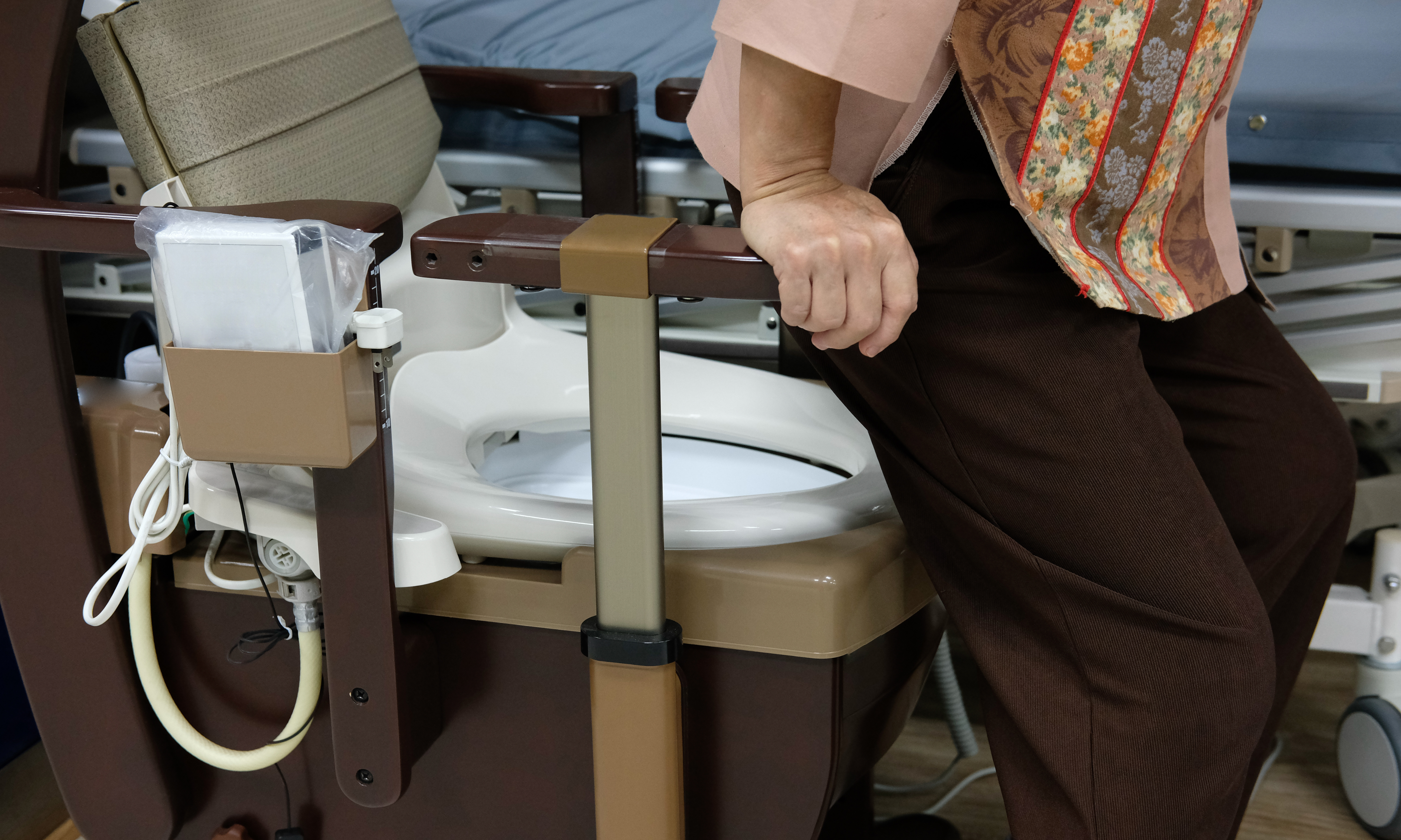An older person sitting down on a commode.