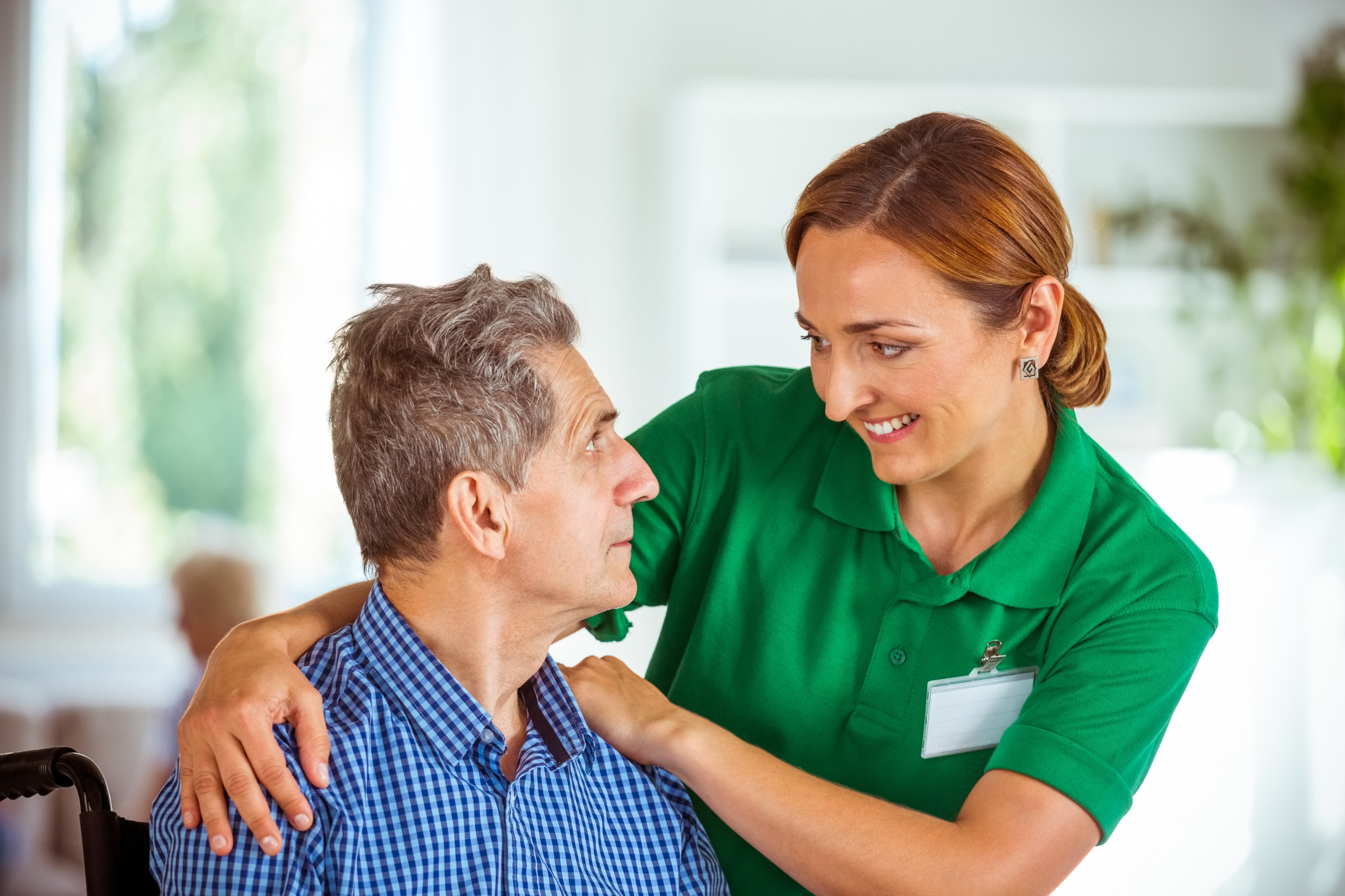 A care worker comforting a male resident who is sat down.