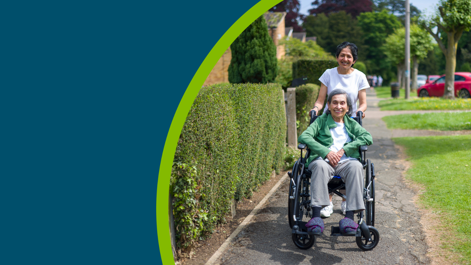 Old Indian woman in wheelchair outdoors on a pavement in a suburban street in summer