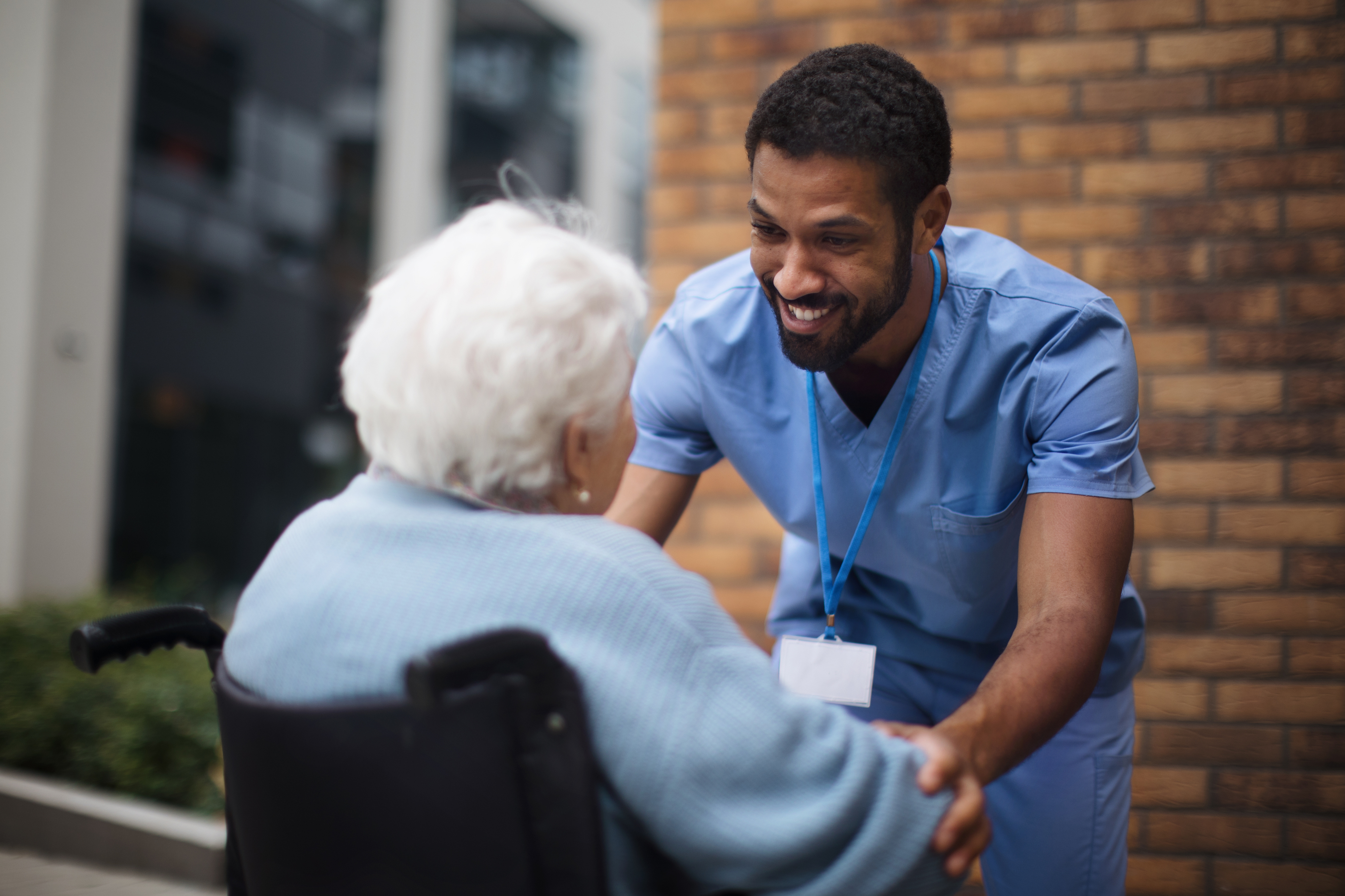 Senior woman at wheelchair spending time outside with her assistant