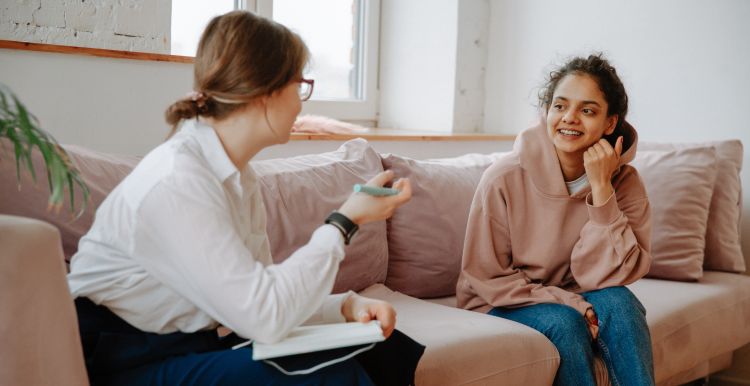 A young person sat on a sofa talking with an adult