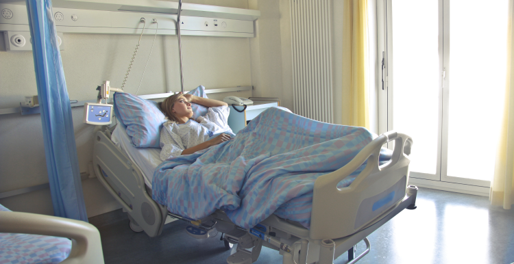 A female patient laying in a hospital bed on her own.