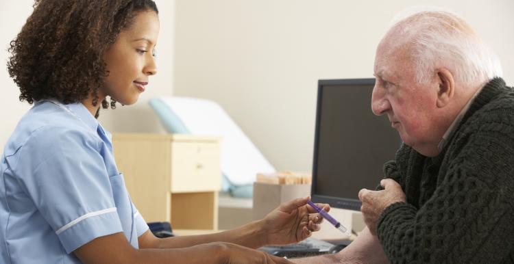 Female nurse injecting senior male patient at a GP practice