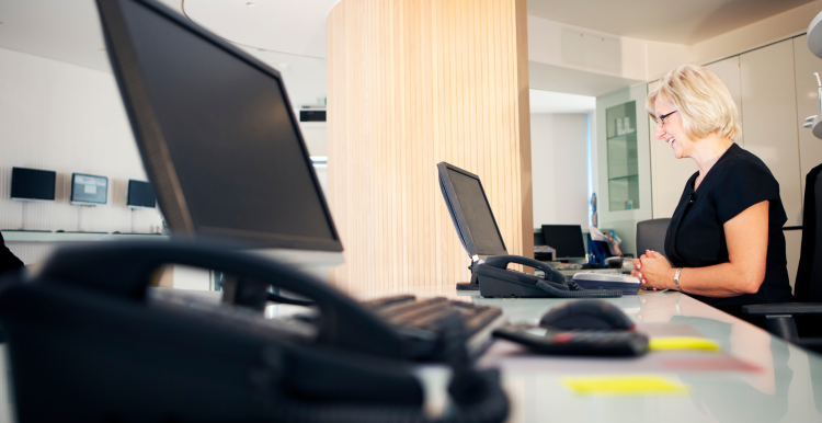 A receptionist sat behind a desk at a GP practice