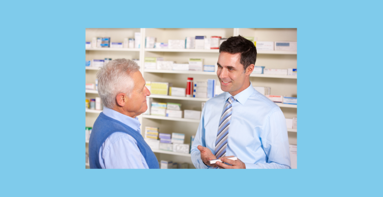 UK pharmacist serving senior man in pharmacy explaining medication.