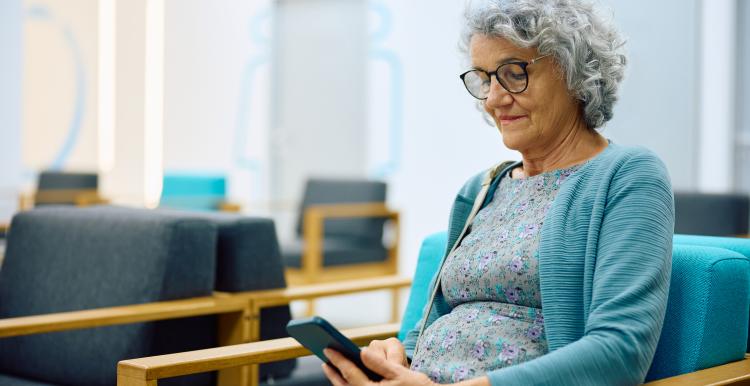 Older woman on her smartphone while waiting for medical appointment at her GP practice.