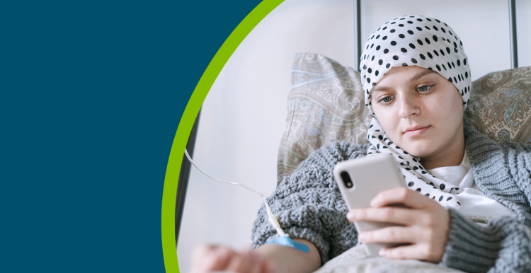 Young cancer patient in a hospital bed looking at her phone.