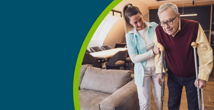 Home caregiver supporting an older man on crutches in his home.