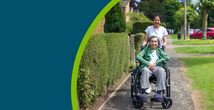 Old Indian woman in wheelchair outdoors on a pavement in a suburban street in summer
