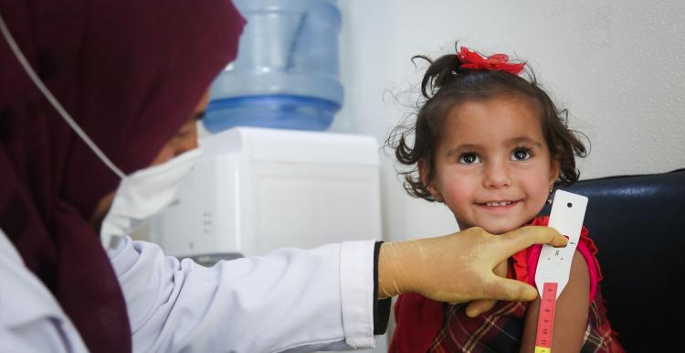A doctor examines a smiling child at a GP practice