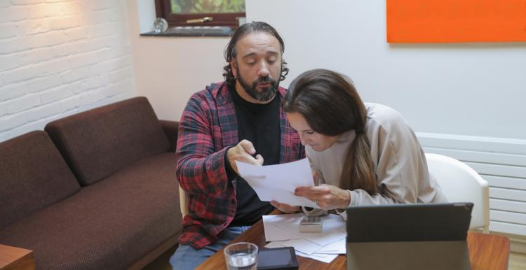 Man and disabled woman doing paperwork at table at home