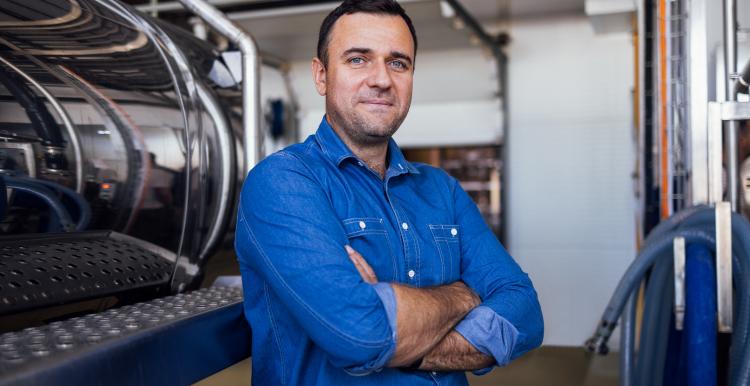 A young male worker near a milk and a butter making machine.