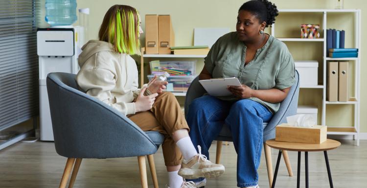 Healthcare member of staff talking with a young woman in a confidential setting.