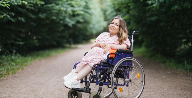 Young lady with spinal muscular atrophy spending warm summer day on fresh air. 