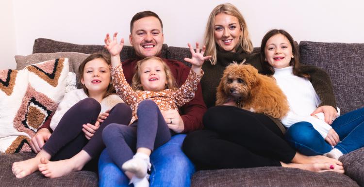 Happy family together at home on the sofa with the dog