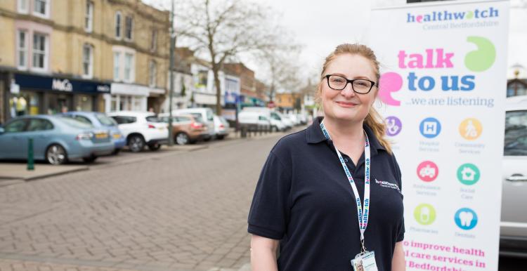 woman stood next to banner at healthwatch event