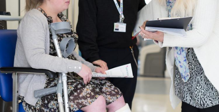 woman sat down in hospital speaking to two people