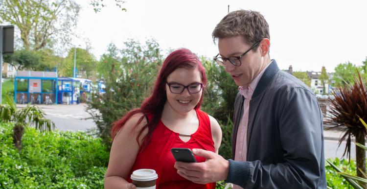 two people stood outside looking at phone