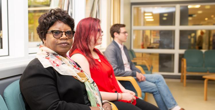 three people sat down in waiting room