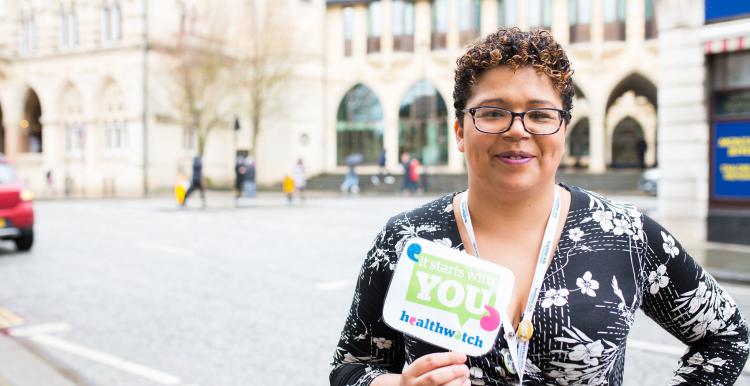 woman stood outside holding leaflet