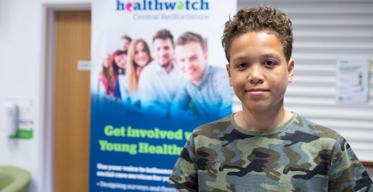 Young male volunteer standing in front of Healthwatch branding