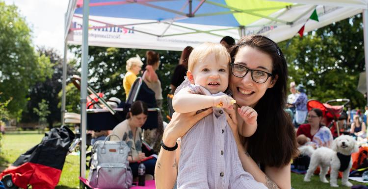 Woman sitting on a picnic blanket with her baby