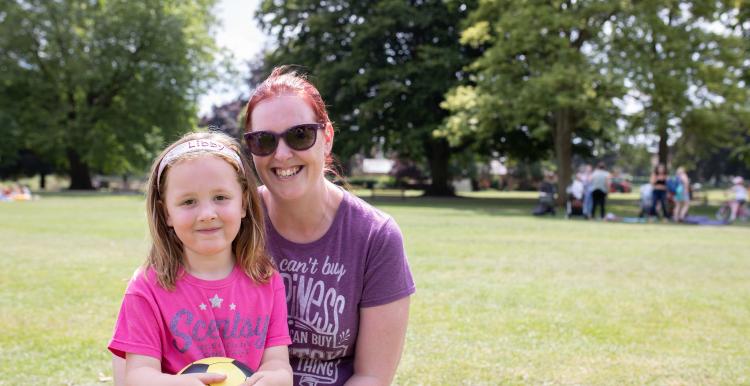 Mother with her arms round her daughter in the park