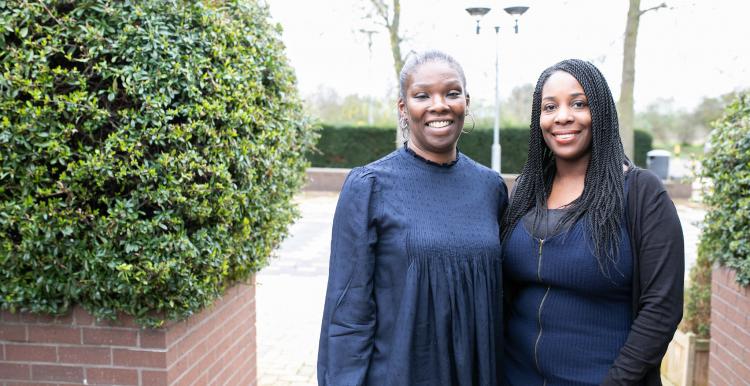 Two women stood in a courtyard with their arms round each other