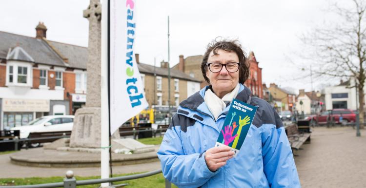 Lady at an outdoor Healthwatch event, holding a leaflet and ready to engage