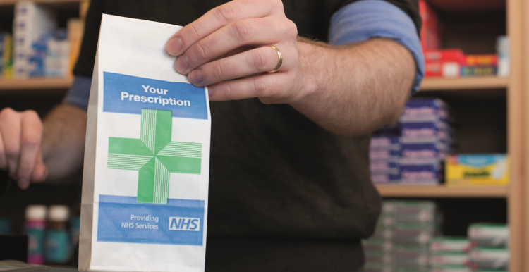 Pharmacist holding an NHS prescription bag