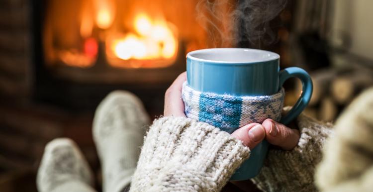 Person wearing white gloves and holding a mug of a hot drink