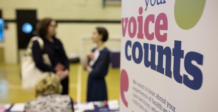 Poster saying "Your voice counts" and two people talking in the background
