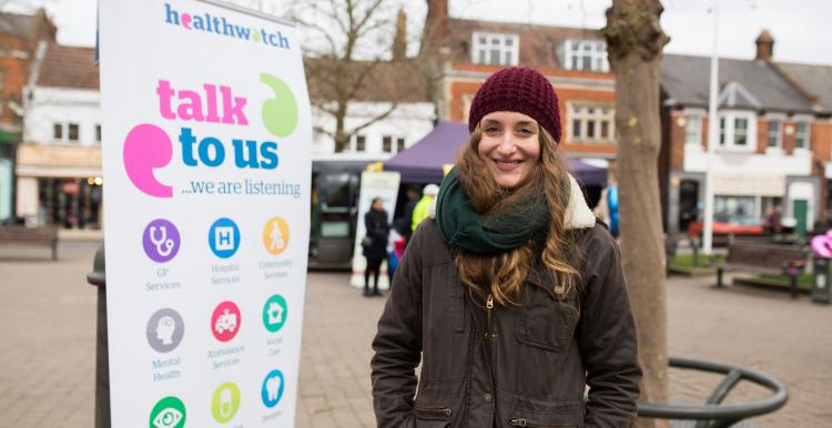 Woman stood in front of a Healthwatch banner