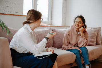 A young person sat on a sofa talking with an adult