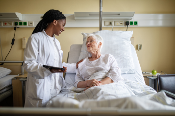 A lady in a hospital bed with a doctor visiting her
