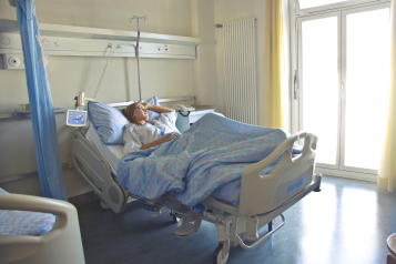 A female patient laying in a hospital bed on her own.