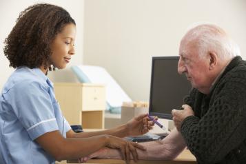 Female nurse injecting senior male patient at a GP practice