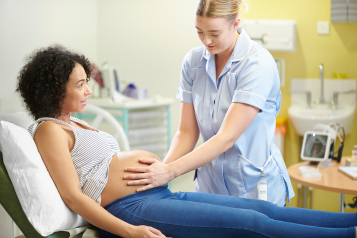 A midwife examining a pregnant woman whilst in hospital.