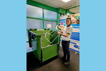 A young person placing a walking aid into a recycling bin at a hospital.