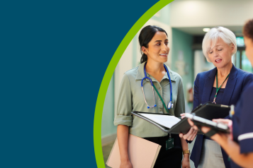 Three NHS healthcare professionals in a hospital corridor looking at some information.
