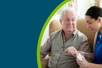 Older man having his arm bandaged in a care home by a nurse whilst he is sat down.
