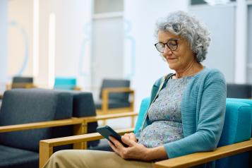 Older woman on her smartphone while waiting for medical appointment at her GP practice.