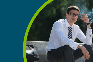 A young man in a shirt and tie sat on a step outside smoking a cigarette.