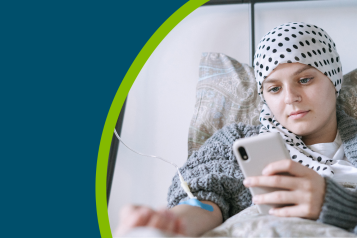 Young cancer patient in a hospital bed looking at her phone.