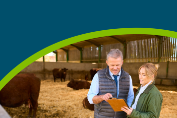 A farmer and a vet in a barn looking at a questionnaire.