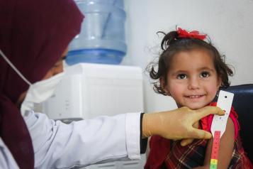 A doctor examines a smiling child at a GP practice