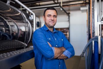 A young male worker near a milk and a butter making machine.