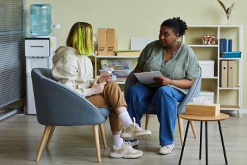 Healthcare member of staff talking with a young woman in a confidential setting.