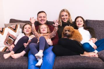 Happy family together at home on the sofa with the dog
