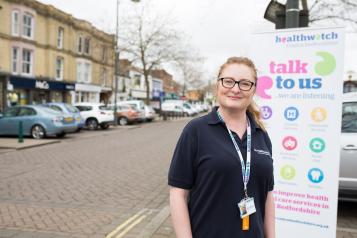 woman stood next to banner at healthwatch event